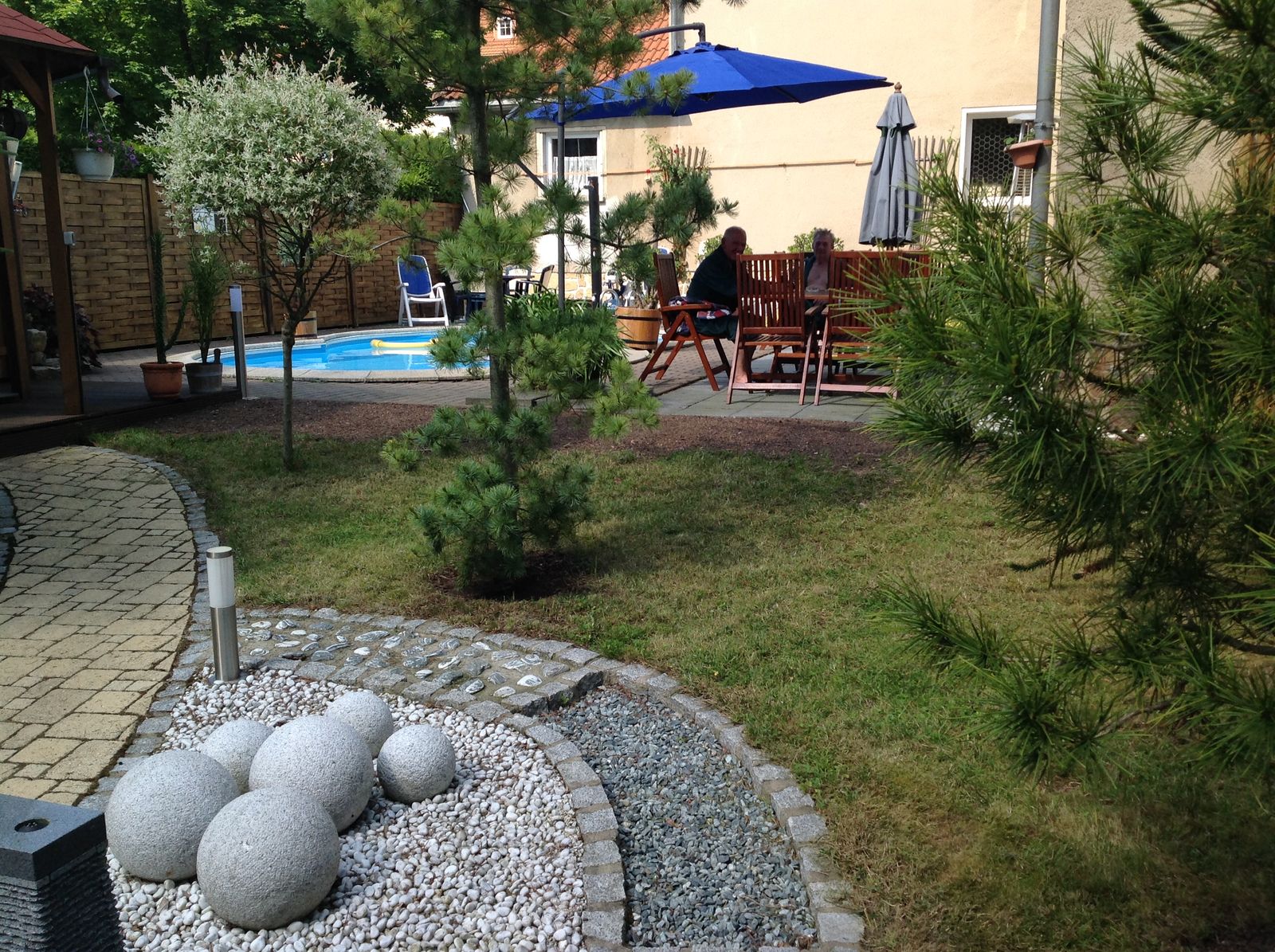 Saunagarten mit Pool, Sonnenschirmen und Grünanlage