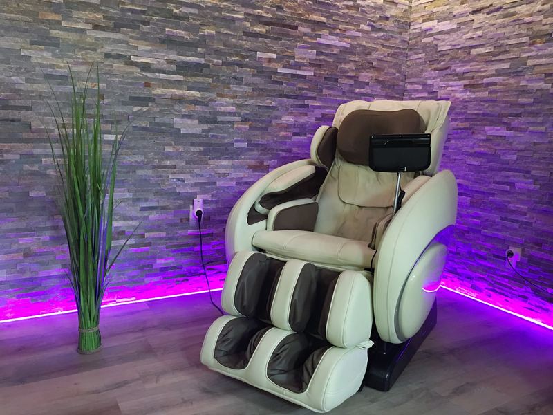 Massagesessel vor farbig beleuchteter Steinwand