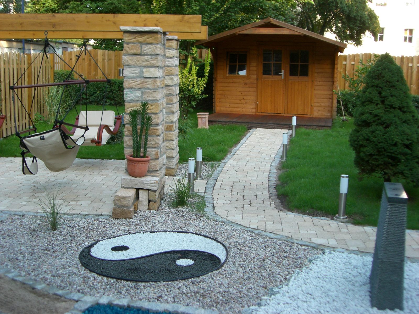Saunagarten mit Yin-Yang-Mosaik, Hängematte und Gartenhaus